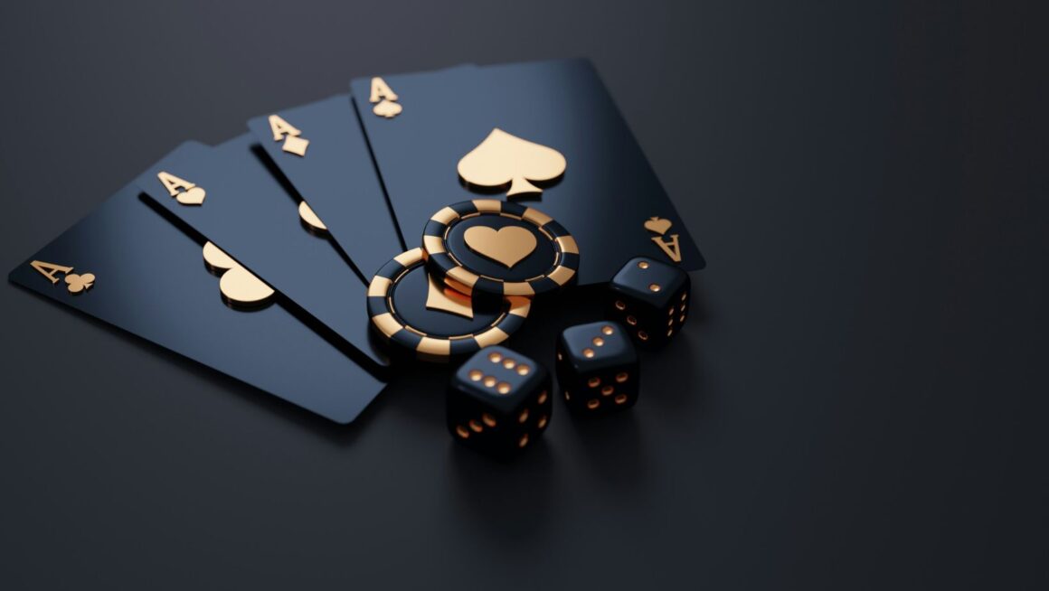 A hand of four aces, poker chips, and dice on a dark surface